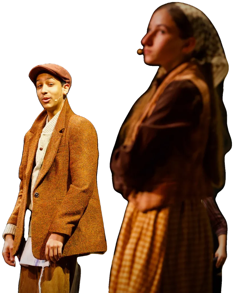 A young man in a flat cap and a young woman in a headscarf stand together in the village, dressed in period costume.