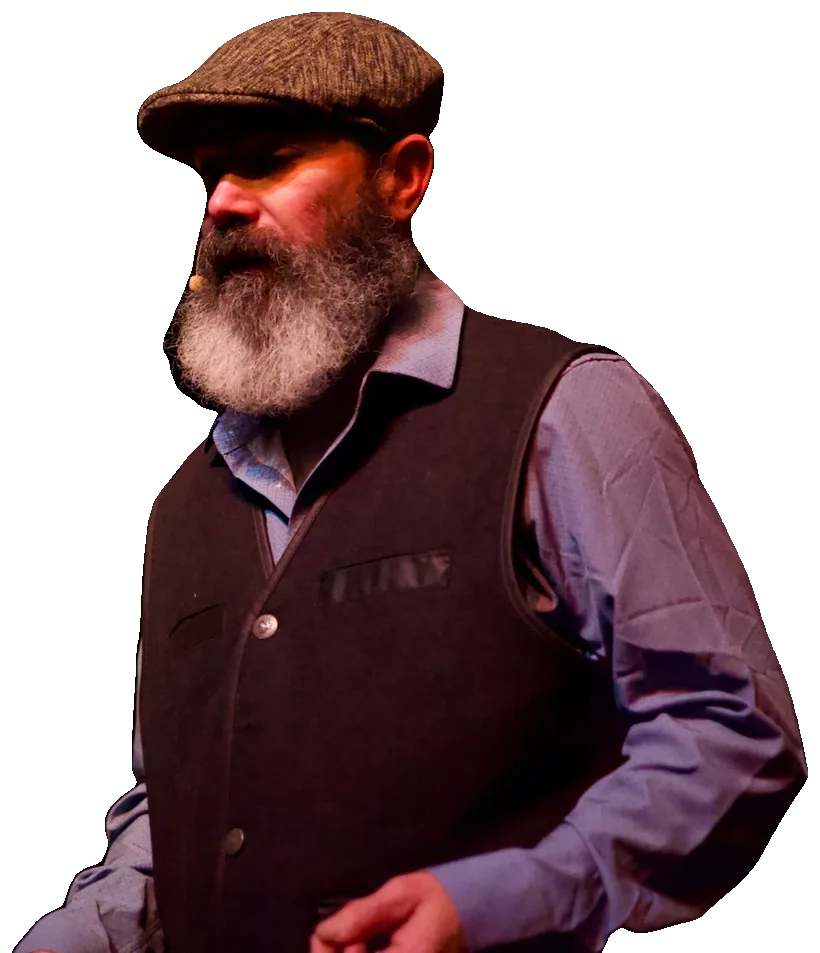 Tevye stands in a warm pool of stage light, his hands loosely clasped.
