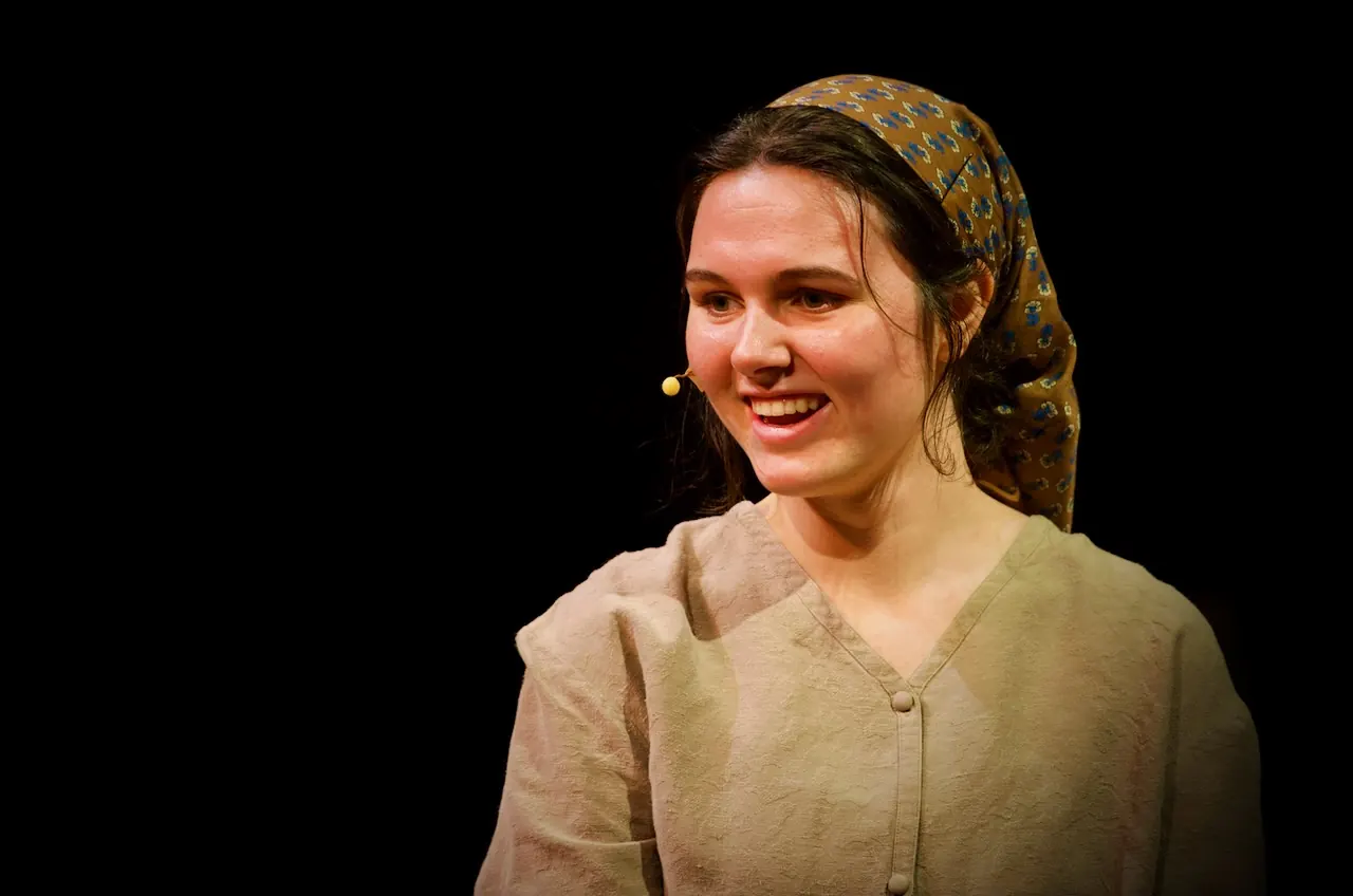 A daughter in a headscarf smiles warmly under the stage lights.