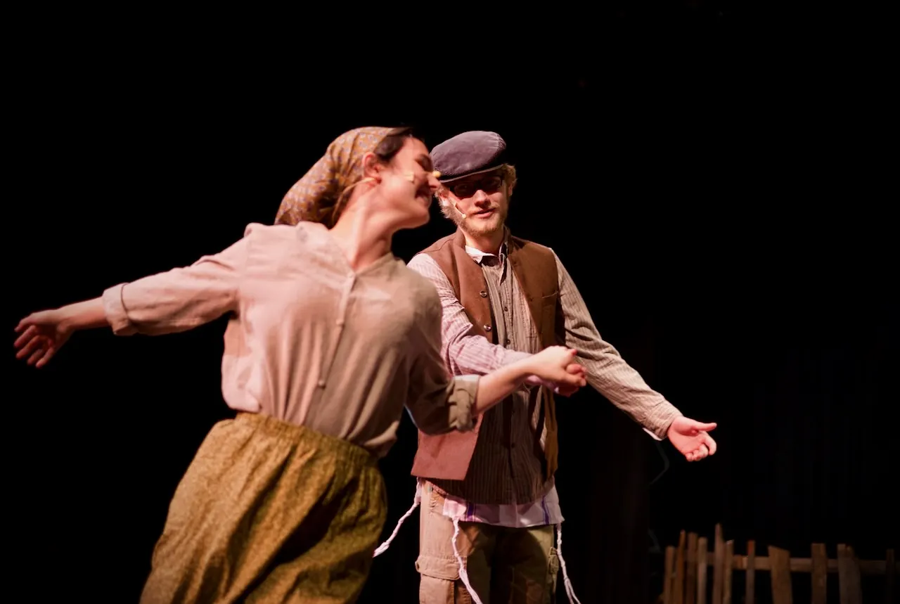 A young woman spins with her arms flung wide as a young man dances beside her.