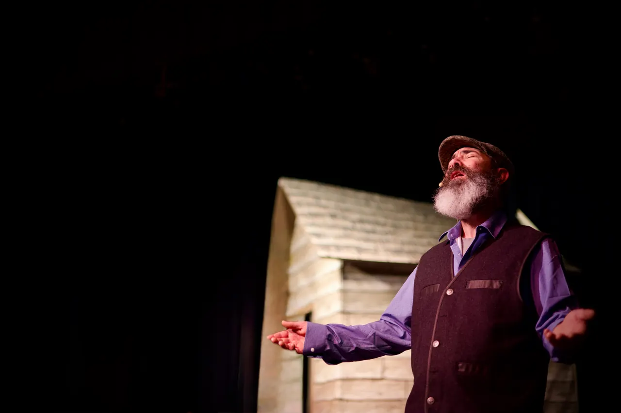 Beside the cottage, Tevye spreads his arms wide as he sings.